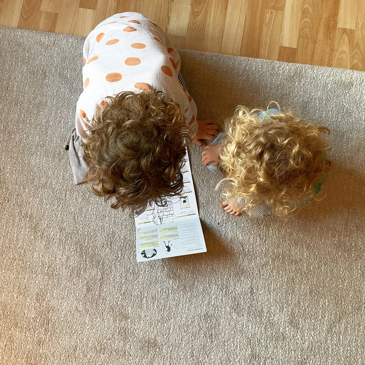 Two small children lying on a carpet playing Mausritter